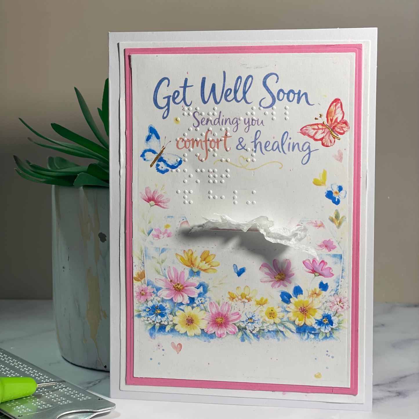 Get well soon card with flowers and butterflies on a marble surface.