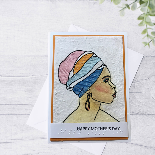Mother's Day card with embroidered design of a woman wearing a colorful headscar on a light wooden surface.