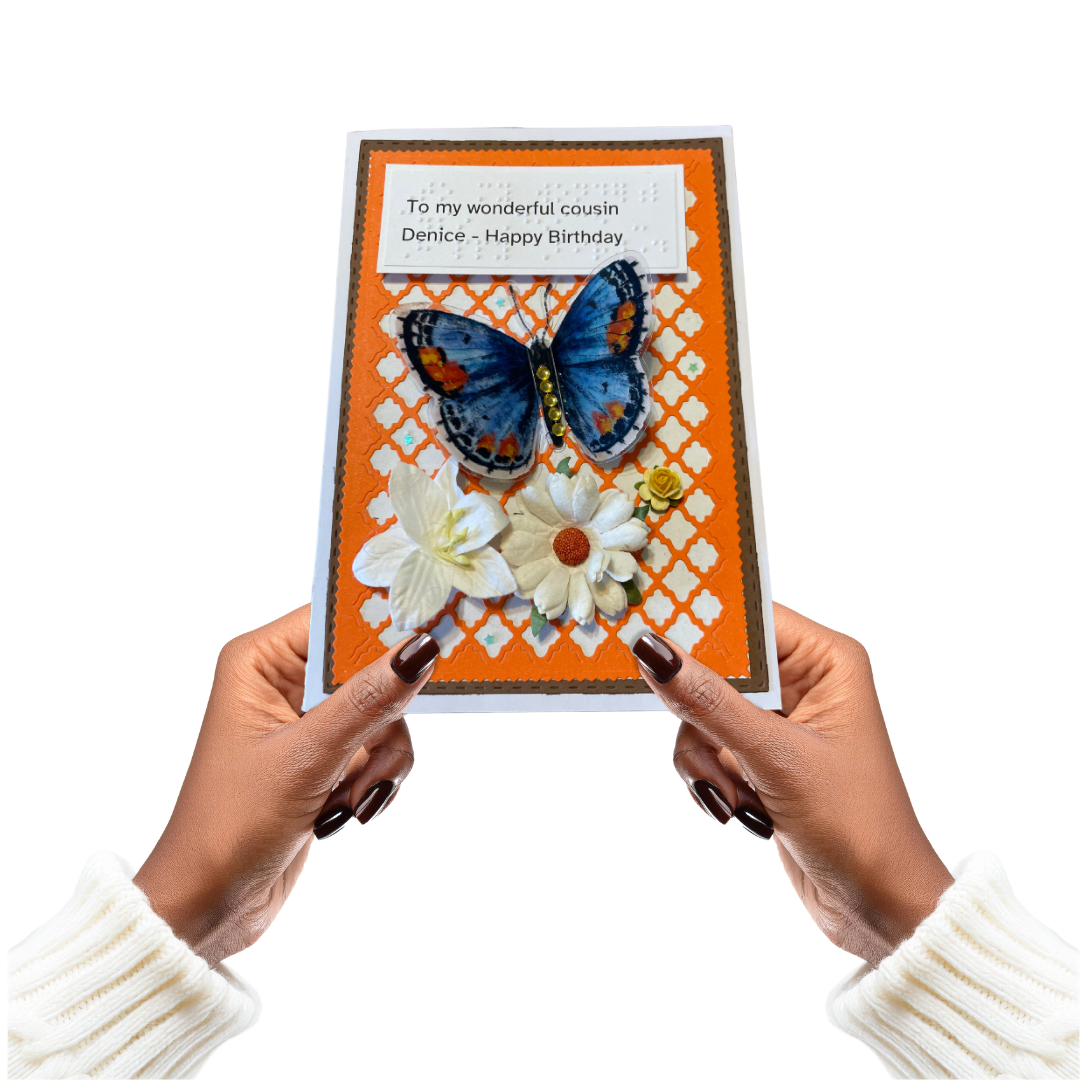 Hand holding a birthday card with a butterfly and flowers on an orange background