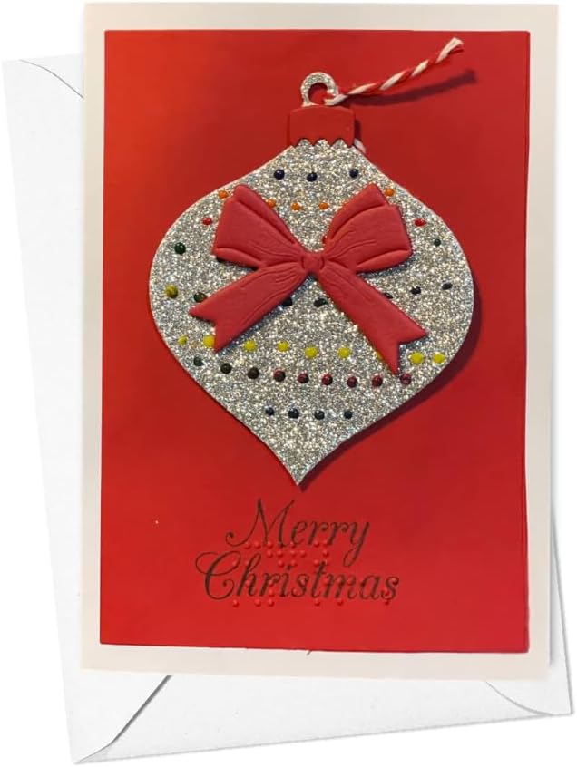 A Christmas greeting card with a red background featuring a glittery silver ornament design with a red bow and the words 'Merry Christmas' in black script. A white envelope is partially visible behind the card.