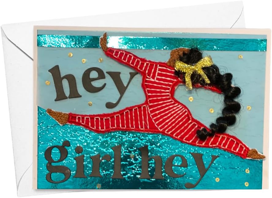 A handmade greeting card with a white envelope behind it. The card features a glittery turquoise background with the text 'hey girl hey' in dark brown letters and a stylized figure of a girl in a red striped leotard with curly black hair and a gold bow.