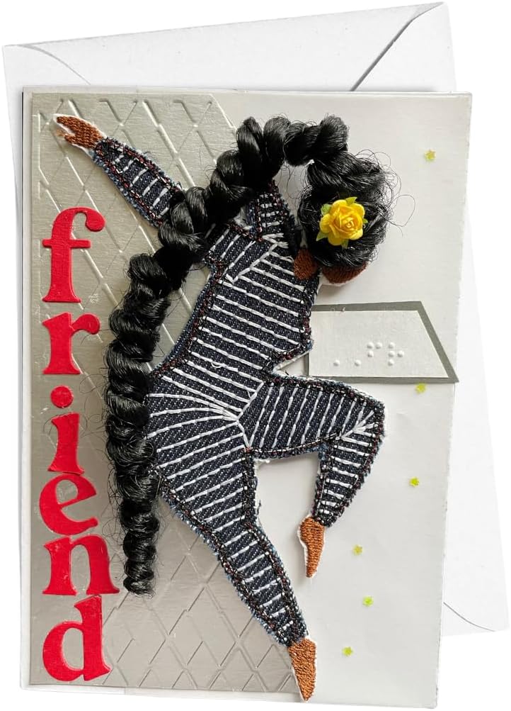 A handmade greeting card featuring a stylized figure made from black yarn hair and black-and-white striped fabric, with a small yellow flower in the hair. The word 'friend' is written vertically in red on the left side.