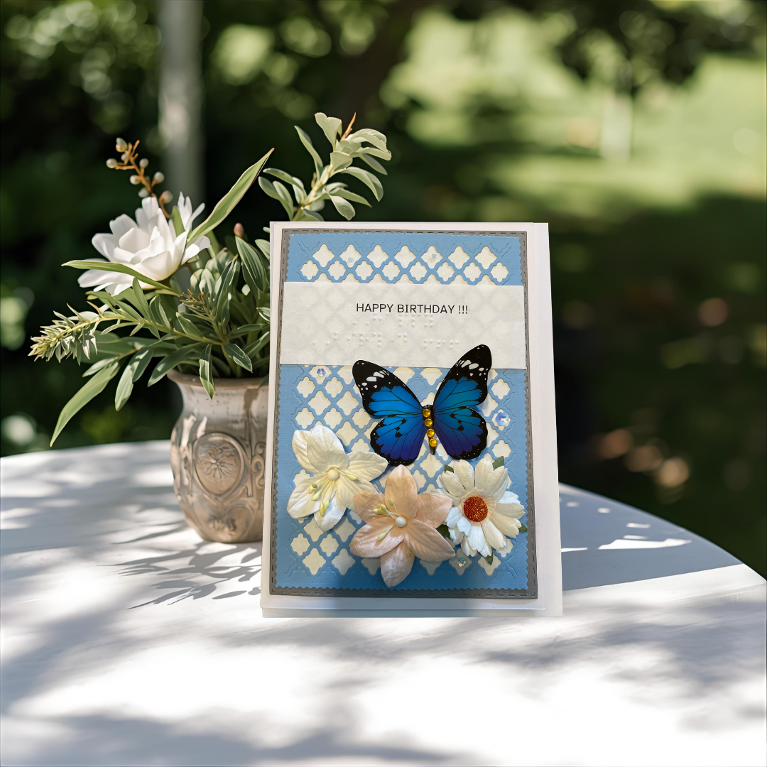 Birthday card with butterfly and flowers on a table outdoors