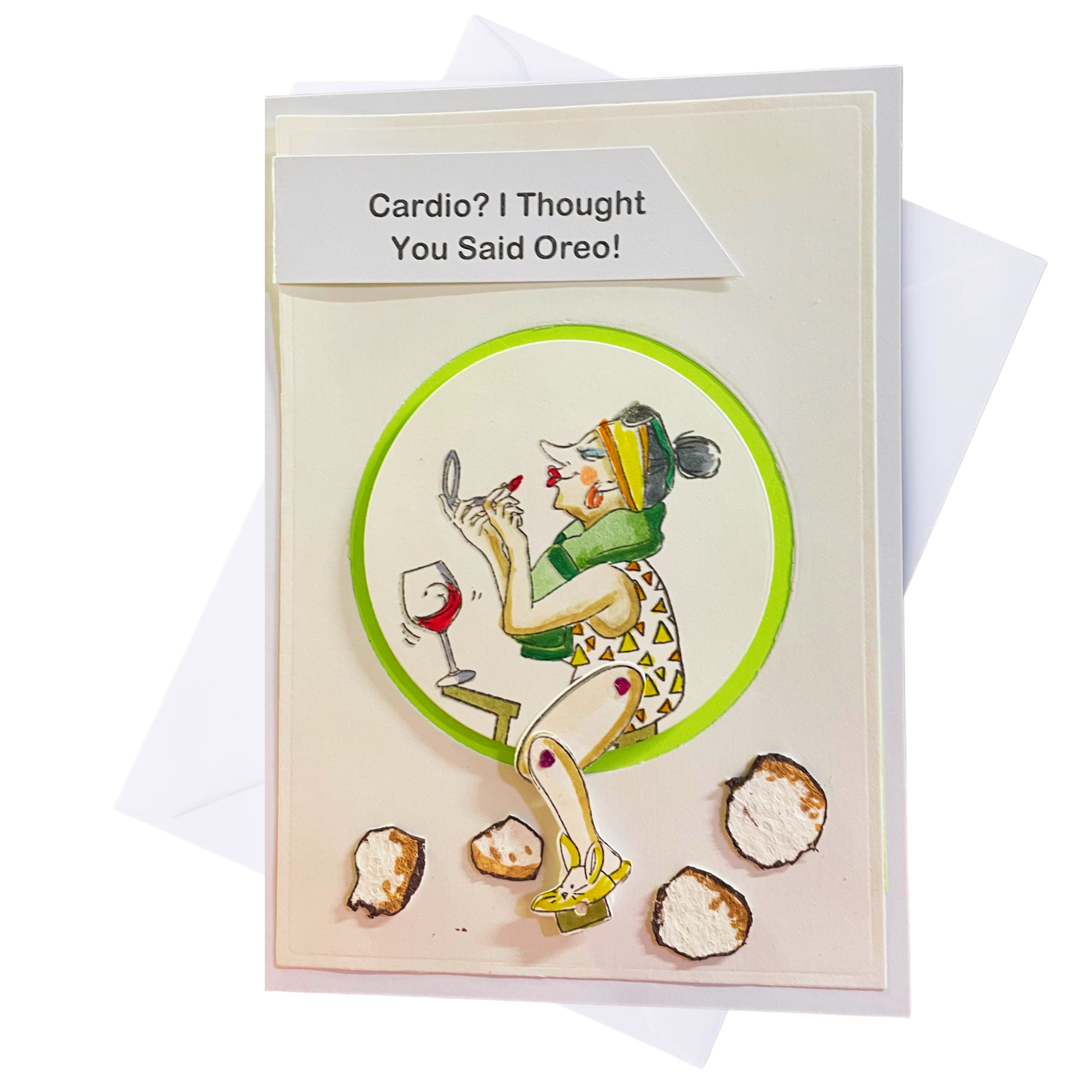 A novelty greeting card with a white envelope behind it. The card features a cartoon illustration of a woman applying lipstick while looking at a mirror, with a glass of red wine and several Oreo cookies.