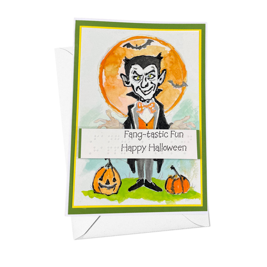 A Halloween greeting card with a white envelope, featuring a cartoon vampire standing in front of an orange full moon, with pumpkins and the text 'Fang-tastic Fun Happy Halloween' on the card.