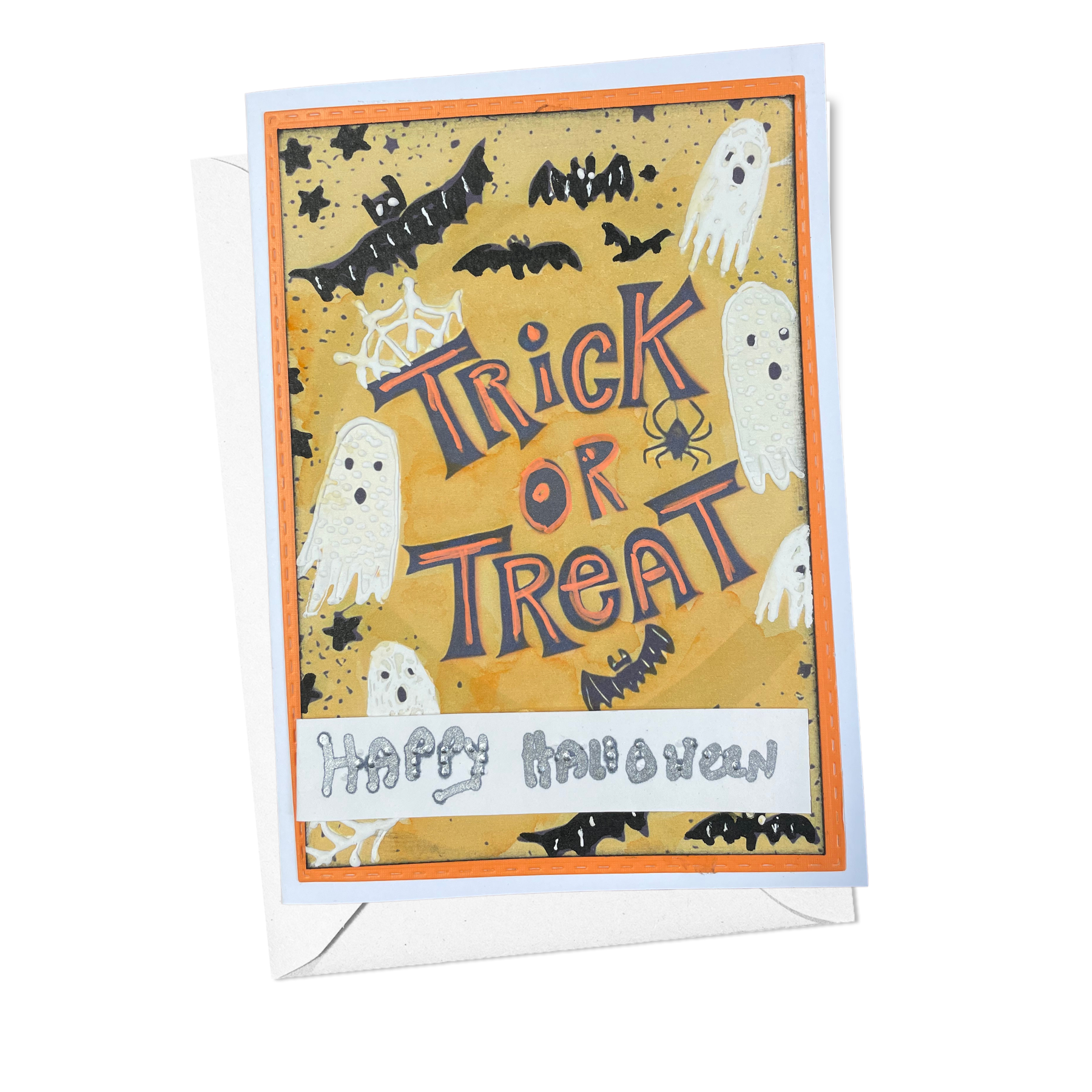 A Halloween greeting card with a white envelope, featuring a tan background with spooky illustrations of ghosts, bats, spiders, and webs, and the words 'Trick or Treat' and 'Happy Halloween'.