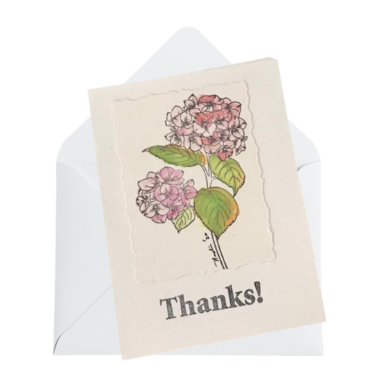 A watercolor card with a vintage-style painting of pink and white hydrangeas and the word 'Thanks!' printed below, shown with a white envelope behind it on a white background.
