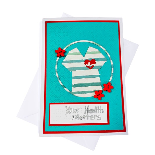 A handmade greeting card featuring a turquoise background with a red border, a white striped beach shirt graphic with red hearts, and a white banner reading 'Your Health Matters'. The card is displayed on top of a white envelope against a clean white background.