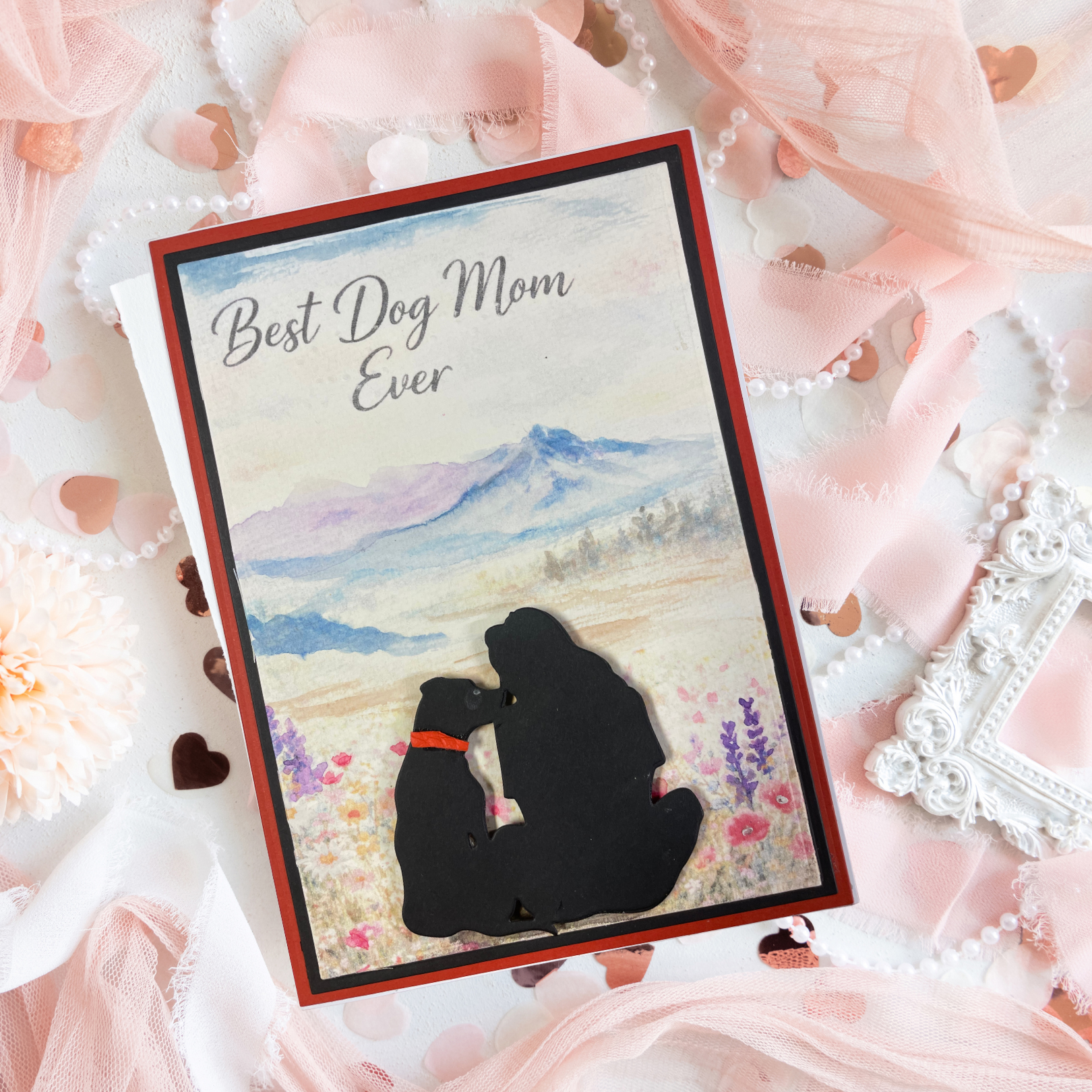 Greeting card with 'Best Dog Mom Ever' text and silhouette of a woman and dog on a scenic background, surrounded by decorative elements.