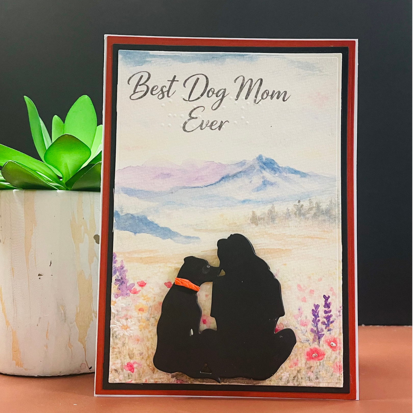 Greeting card with silhouette of a woman and dog, text 'Best Dog Mom Ever', and watercolor landscape.