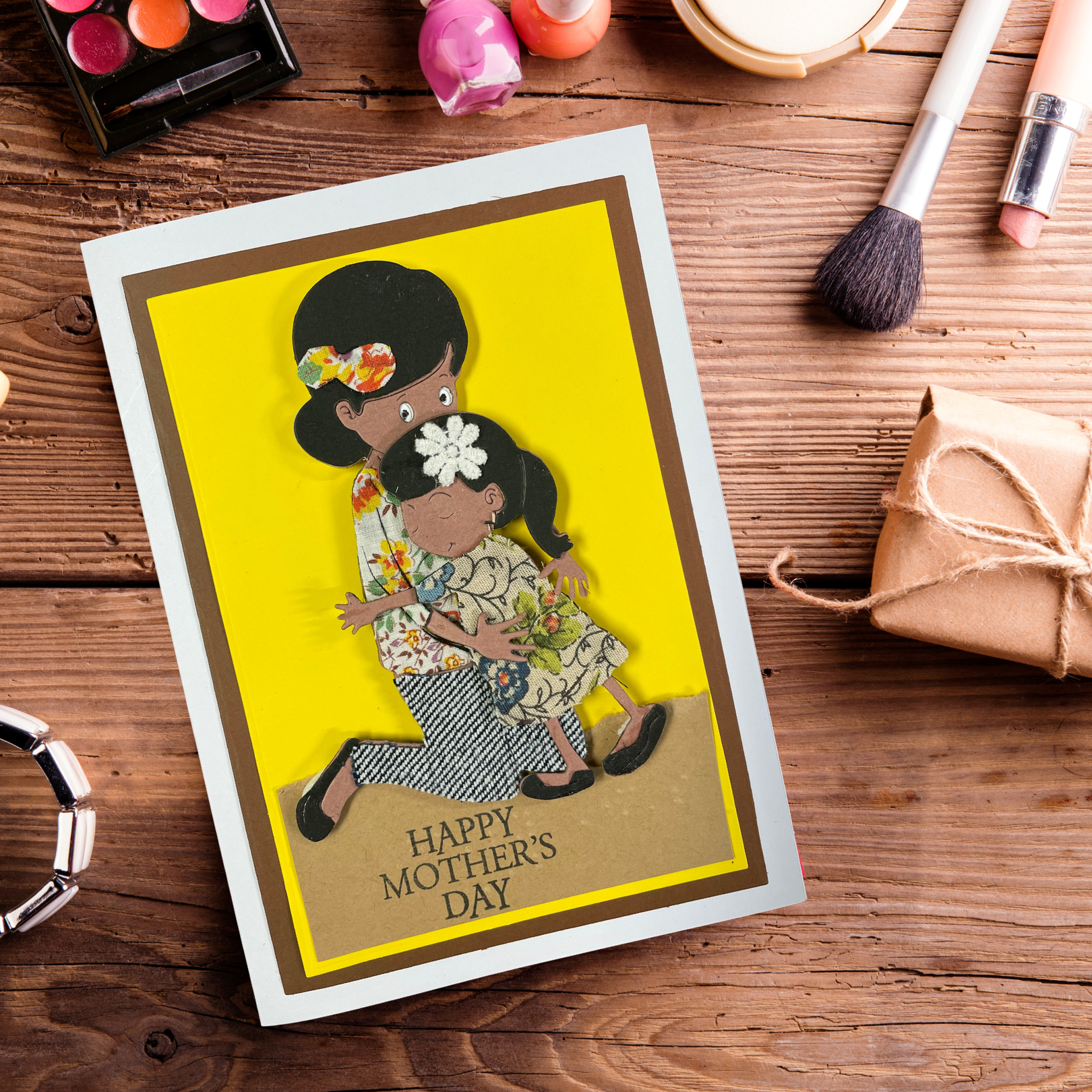 Mother's Day card with a tactile image of a woman and child on a wooden surface with makeup items.