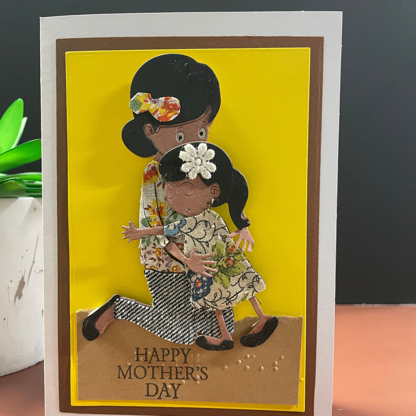 Mother's Day card with tactile images of a woman and child on a yellow background