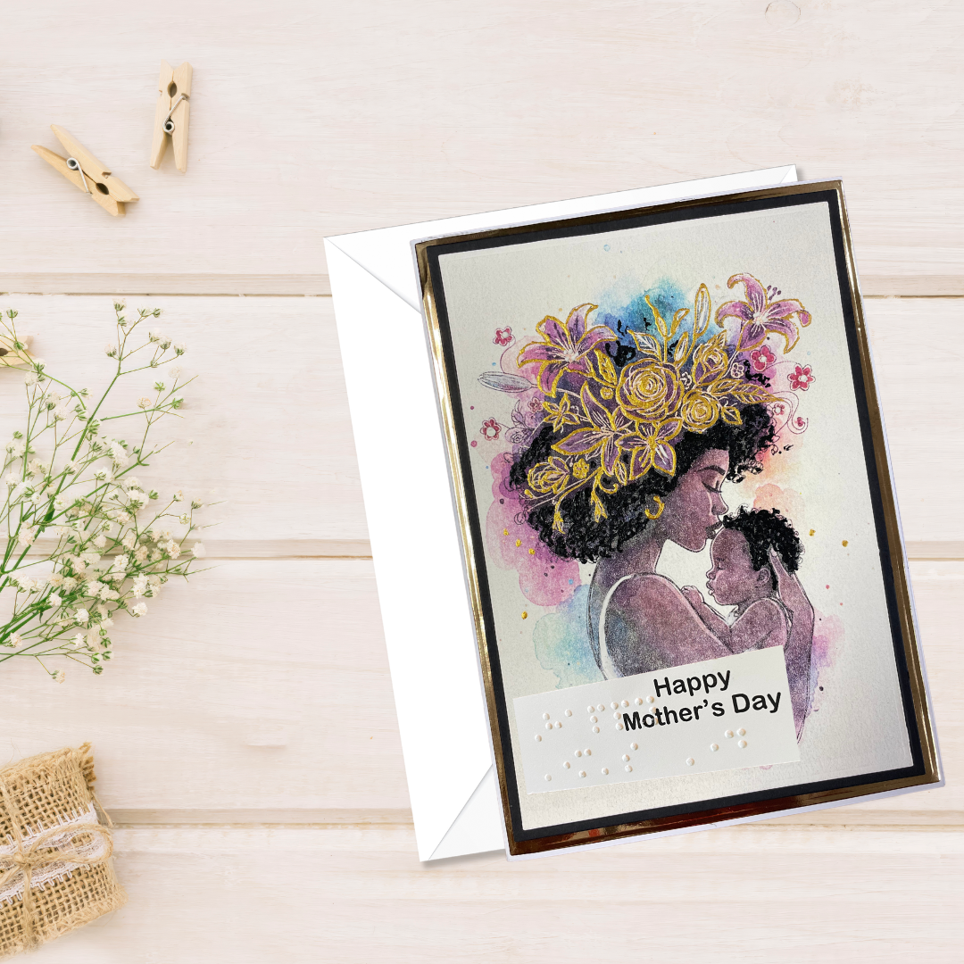 Greeting card with a mother and child illustration and 'Happy Mother's Day' text on a wooden surface.