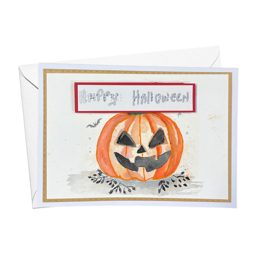 A  Halloween greeting card with a white envelope behind it, featuring a watercolor-style orange jack-o'-lantern and the words 'Happy Halloween' in gray script inside a red-bordered box.