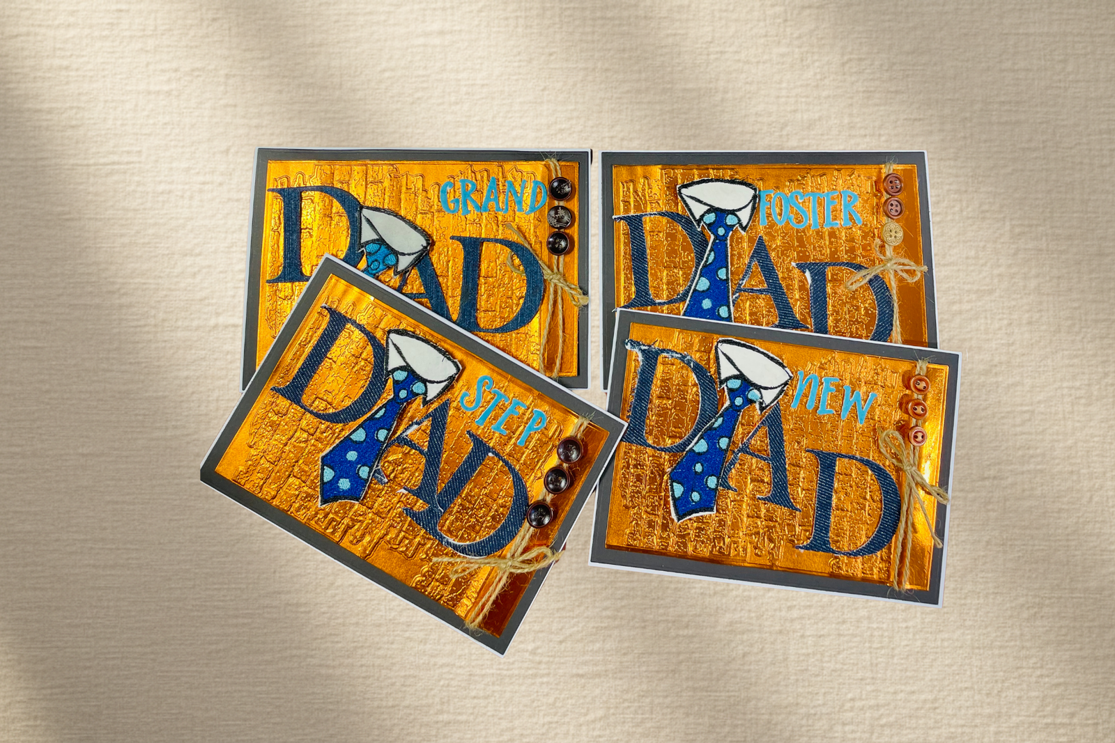 Four greeting cards with 'DAD' text and a tie graphic on a metallic surface