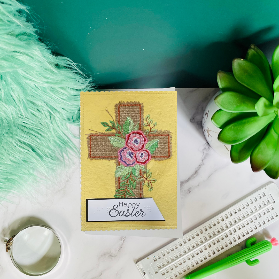 Easter card with floral cross design on a marble surface with decorative items.