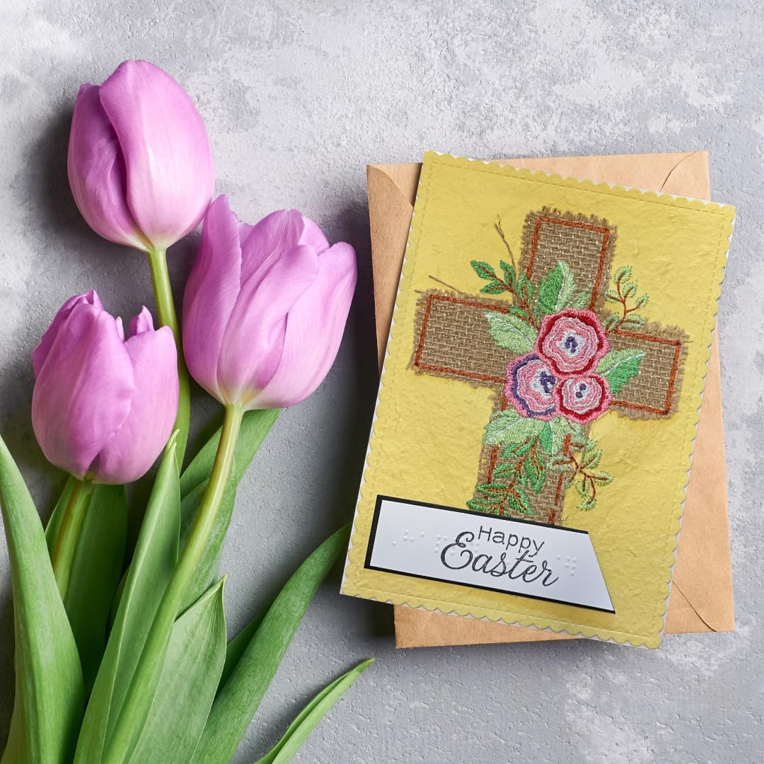 Yellow Easter card with cross and flowers design, next to pink tulips on a gray surface