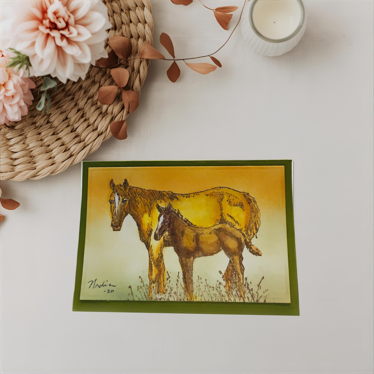 Card with illustration of two horses on a white surface with flowers and a candle.