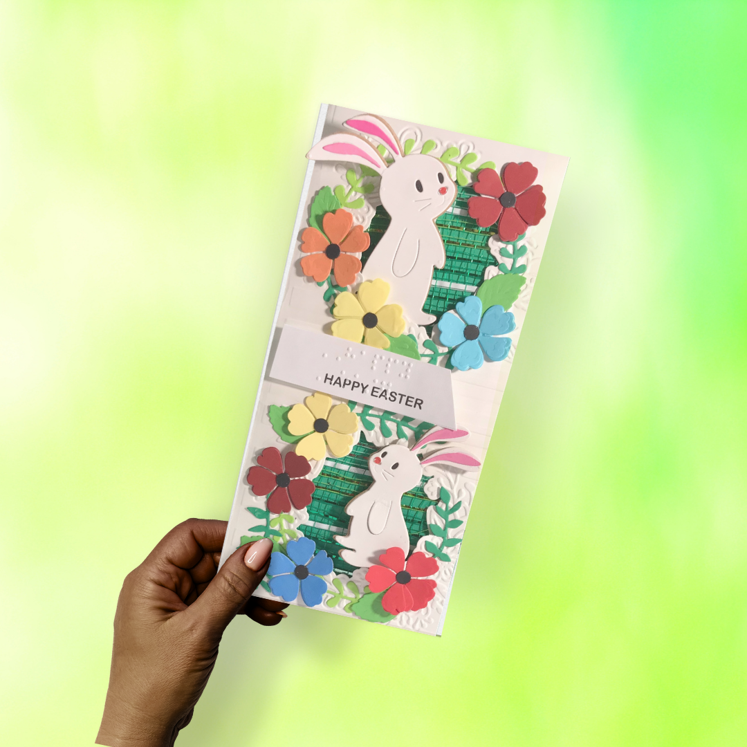 Hand holding a decorative Easter card with bunnies and flowers on a gradient background