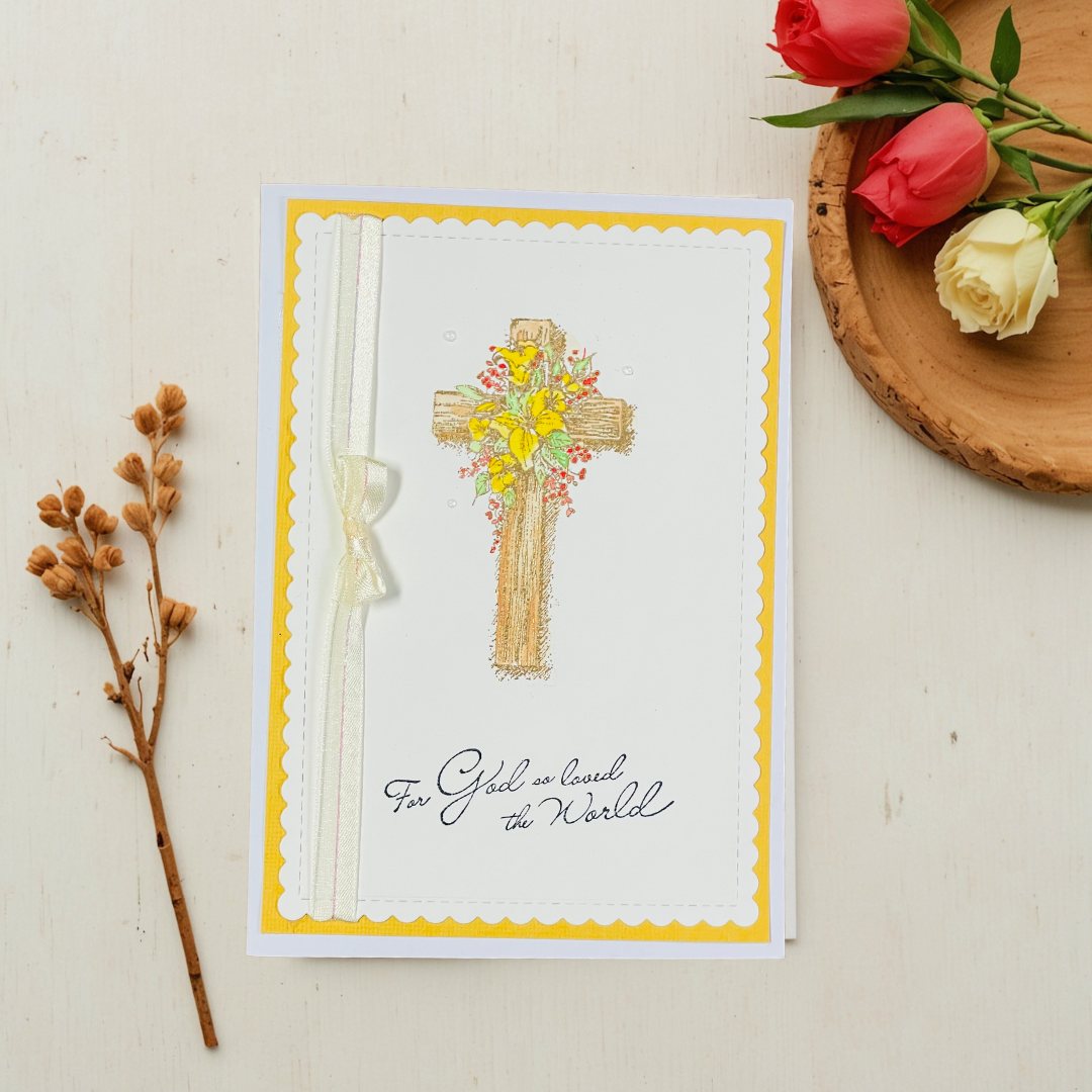 Greeting card with decorative cross and flowers on a white surface with flowers and branches.