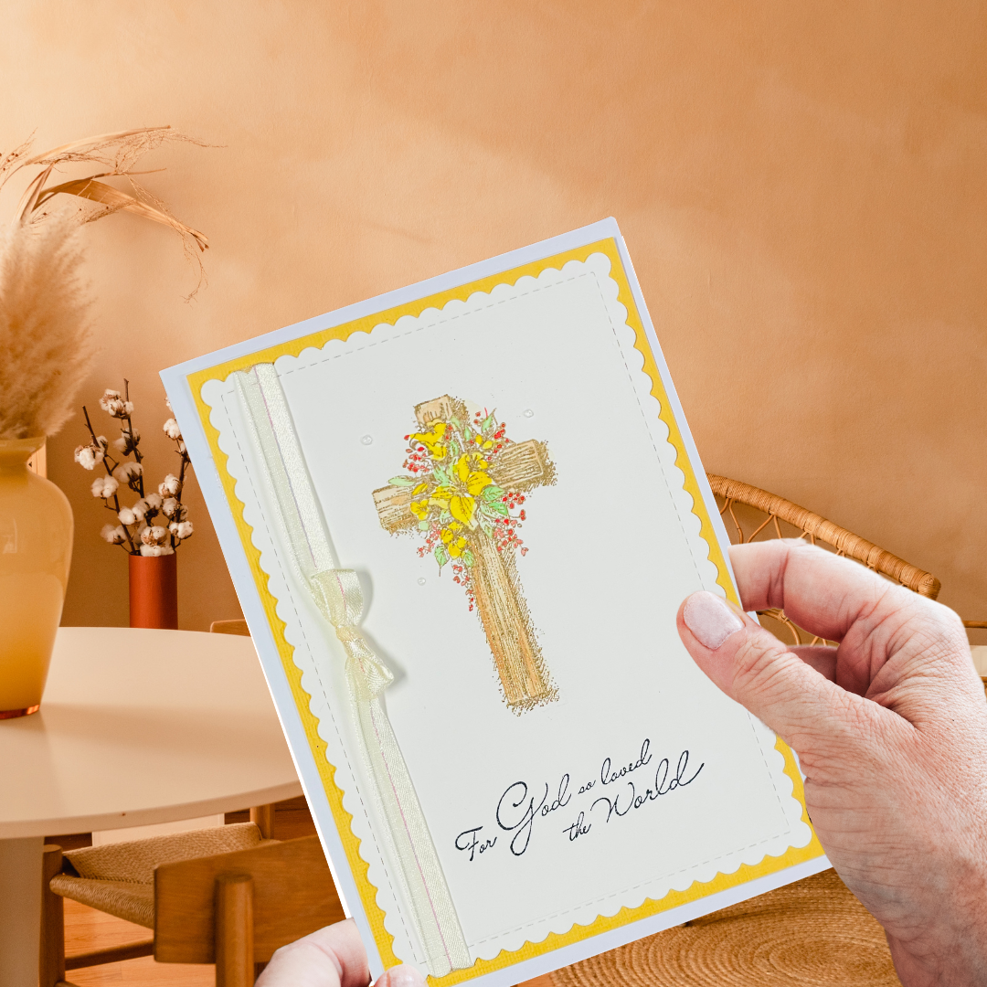 Hand holding a greeting card with a cross and flowers design 