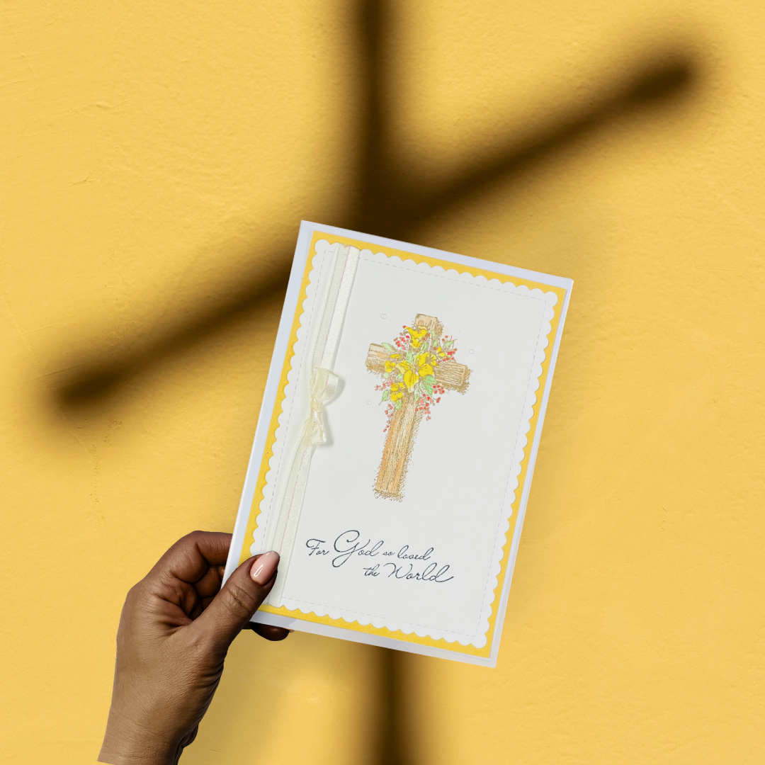 Hand holding a card with a cross design on a yellow background