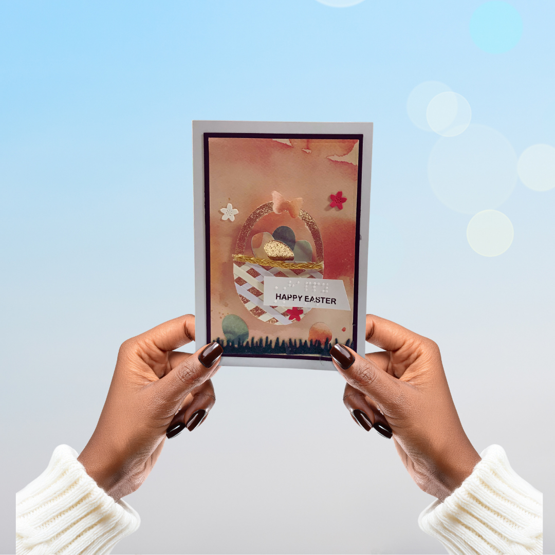 Person holding a 'Happy Easter' card with a basket and eggs design against a light blue background.
