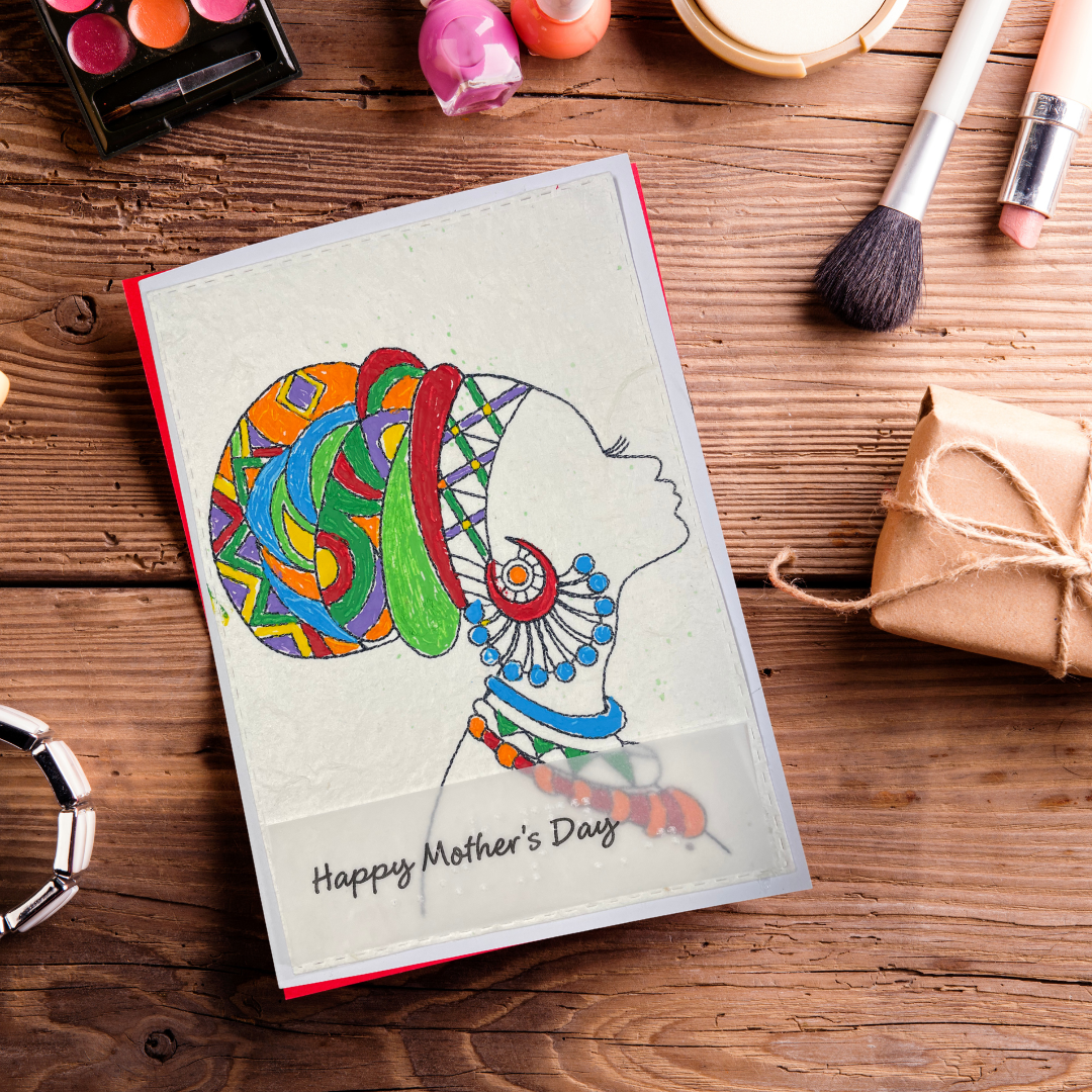 Mother's Day card features a hand-drawn profile silhouette of a woman adorned with a vivid geometric head wrap in orange, red, green, blue, and purple, paired with layered statement jewelry in matching jewel tone 'Happy Mother's Day' text on a wooden surface with makeup items.