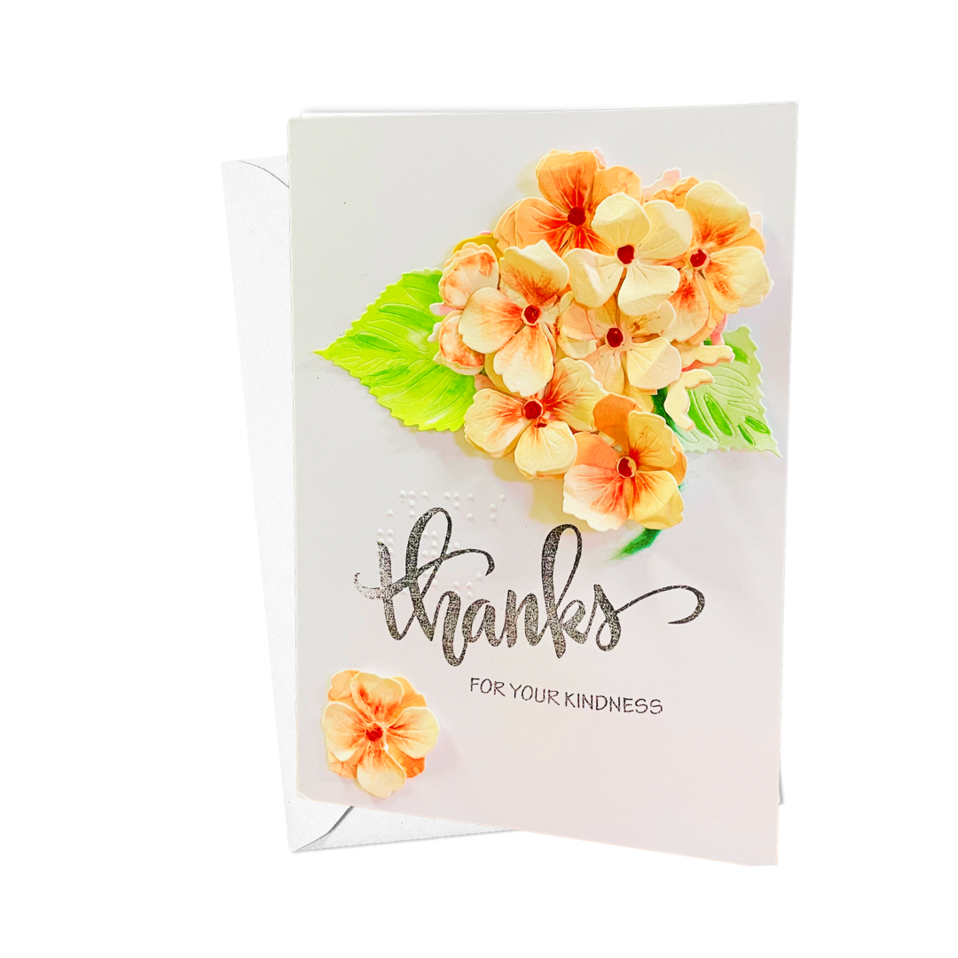 A white greeting card with a matching envelope, decorated with 3D orange and Peach Hydrangea Bouquet, green leaves, and silver foil script reading 'thanks FOR YOUR KINDNESS'.