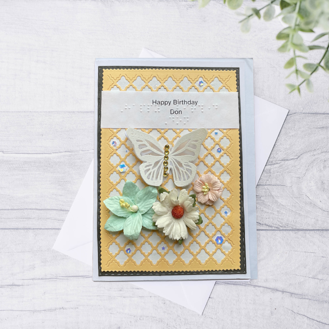 Handmade birthday card with butterflies and flowers on a textured surface