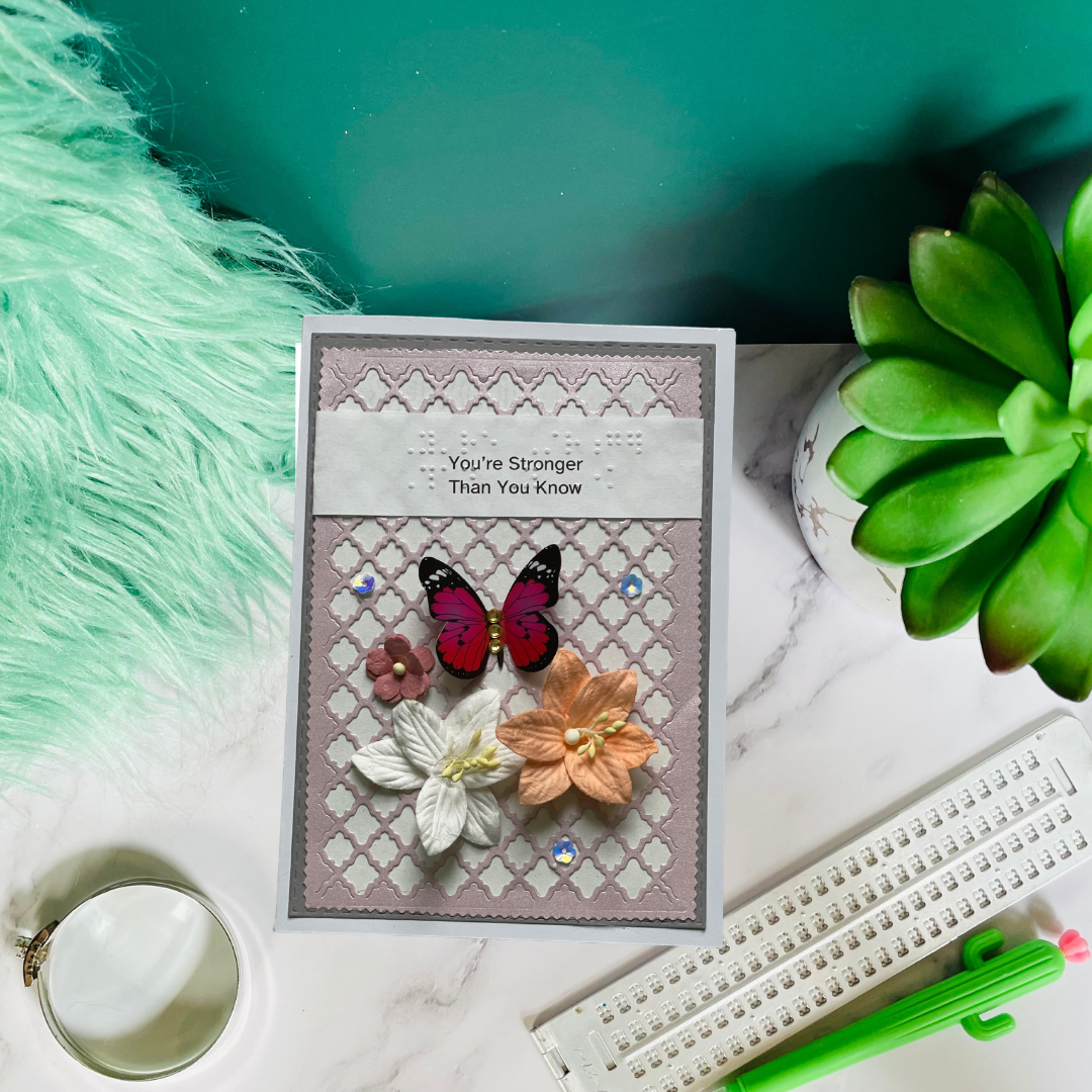 Card with butterfly and flower design on a marble surface with a plant