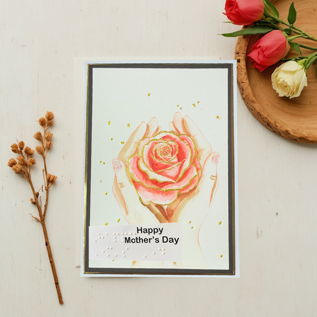 Mother's Day card with a rose design on a light surface with flowers and branches.
