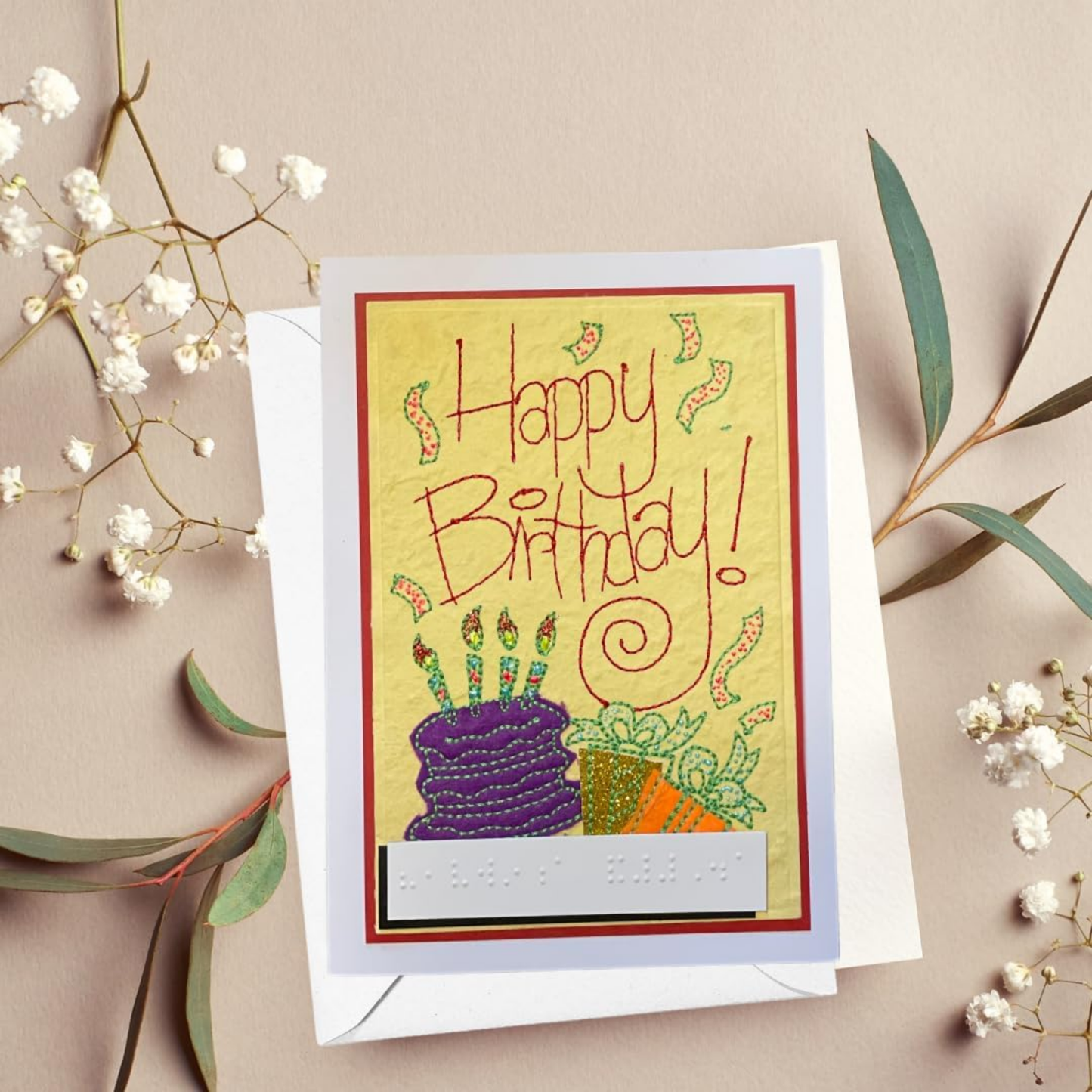 Emboirdery Birthday card with colorful cake illustration and 'Happy Birthday!' text on a beige background with flowers.
