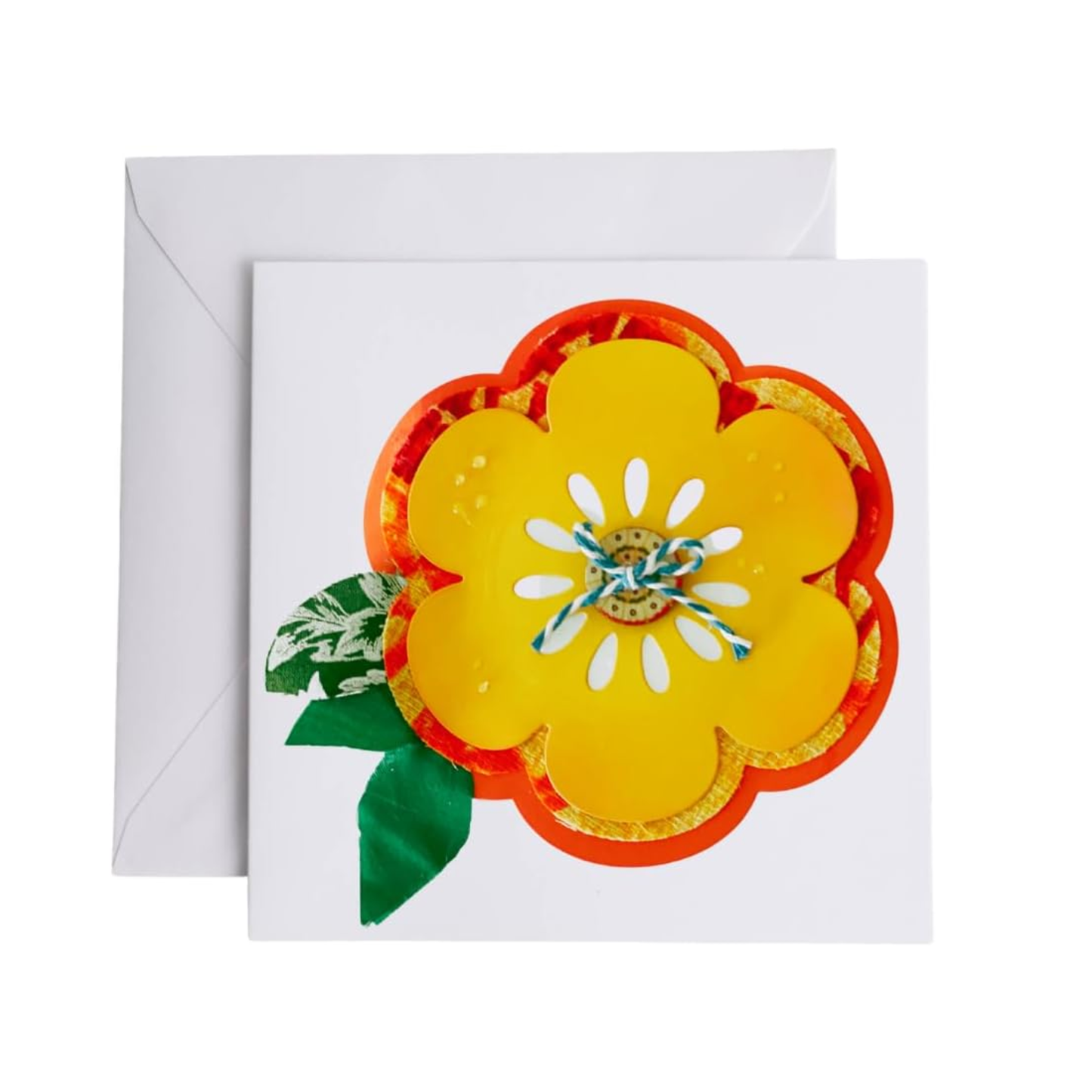 A square white greeting card with a large decorative yellow flower design outlined in orange and gold, with green leaves and a blue-and-white ribbon center, shown with a white envelope behind it on a light gray background.