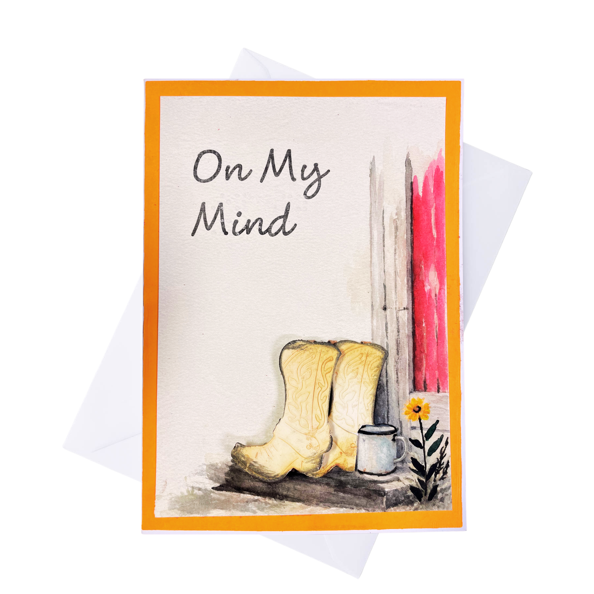 A greeting card with an orange border and the handwritten text and braille 'On My Mind,' featuring a watercolor-style illustration of off white cowboy boots, a white mug, a small yellow flower, and a red vertical brushstroke on a white background. A white envelope is partially visible behind the card.